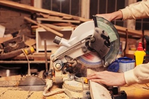 carpenter cutting wooden beam using table saw in workshop 